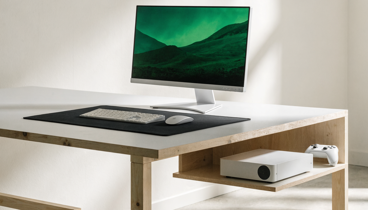 Console blanche, manette, clavier et souris organisés autour d’un tapis sur un bureau