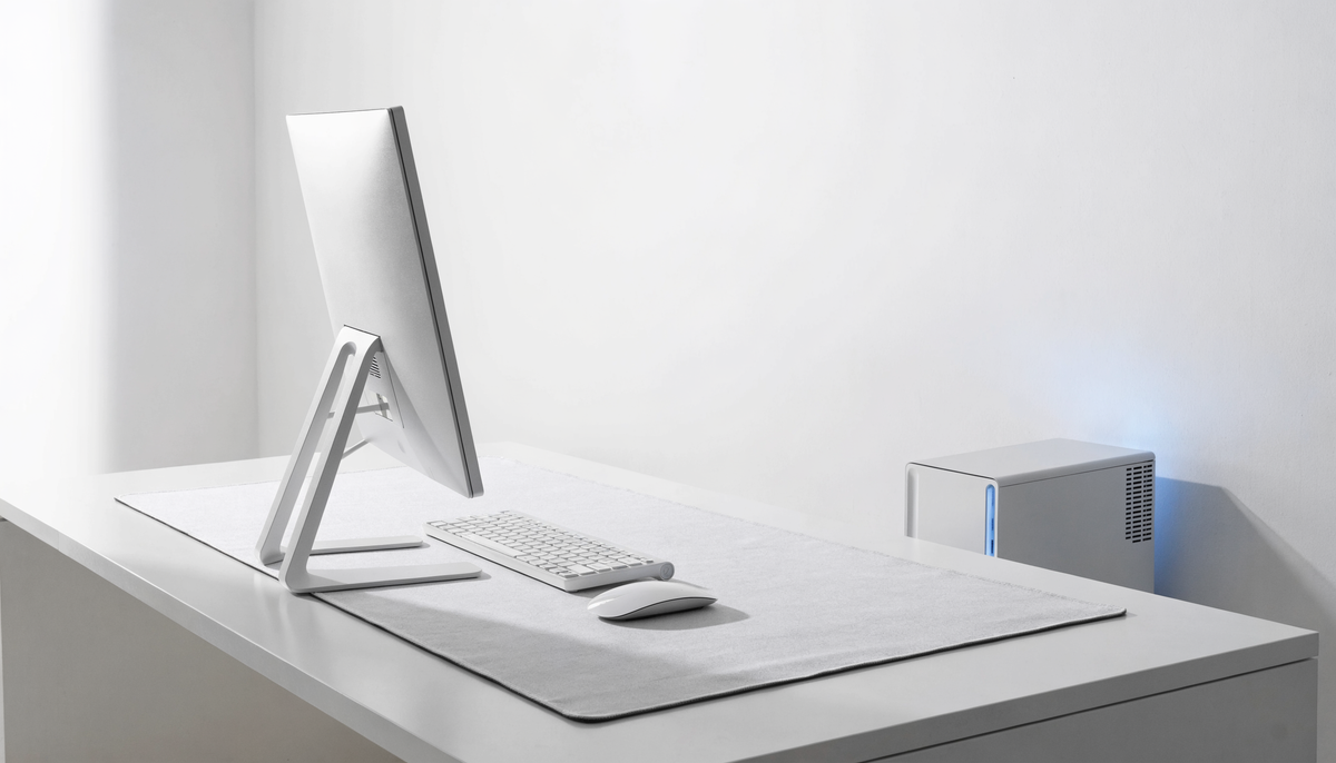 Setup gaming blanc avec clavier clair et tapis gris pâle sur un bureau dégagé